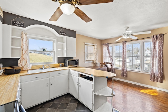 kitchen featuring dark hardwood / wood-style floors, white cabinetry, sink, kitchen peninsula, and a textured ceiling