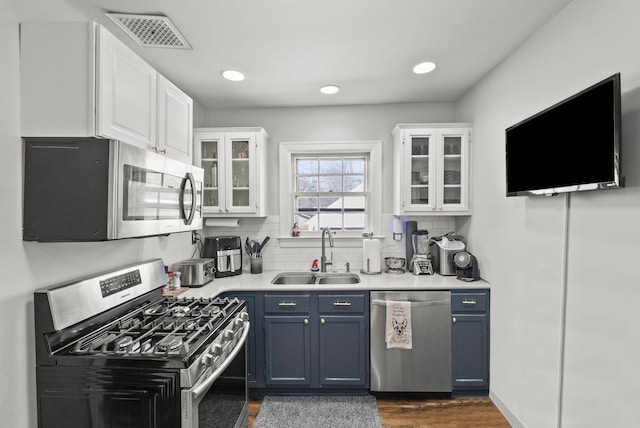 kitchen with a sink, white cabinets, visible vents, and stainless steel appliances