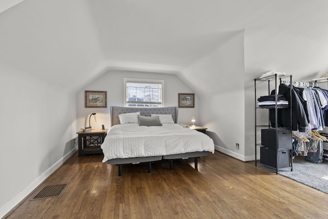 bedroom featuring visible vents, baseboards, lofted ceiling, and hardwood / wood-style floors