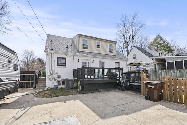 back of house with a deck, a shingled roof, central AC, and fence