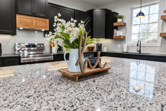 kitchen with sink, hanging light fixtures, electric stove, light stone countertops, and decorative backsplash