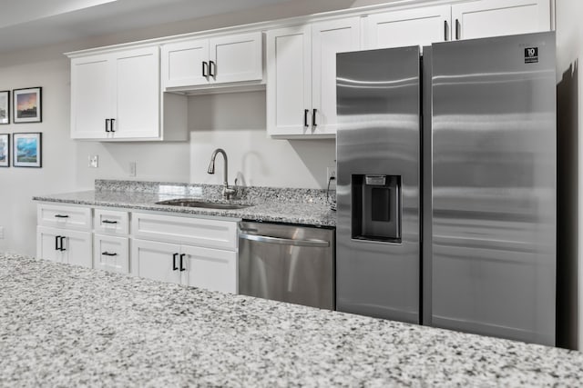 kitchen featuring white cabinetry, sink, light stone counters, and stainless steel appliances