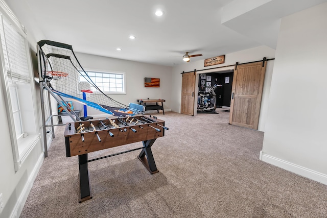 recreation room featuring a barn door, ceiling fan, and carpet flooring