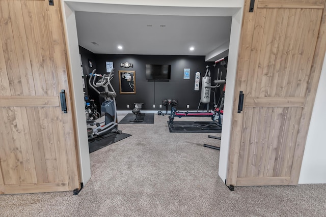 workout room featuring a barn door and carpet