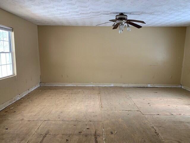 empty room with a textured ceiling and ceiling fan