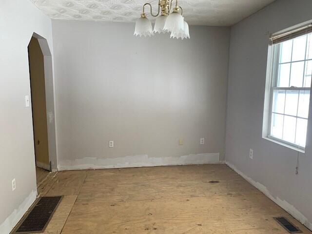 spare room featuring a healthy amount of sunlight and a chandelier