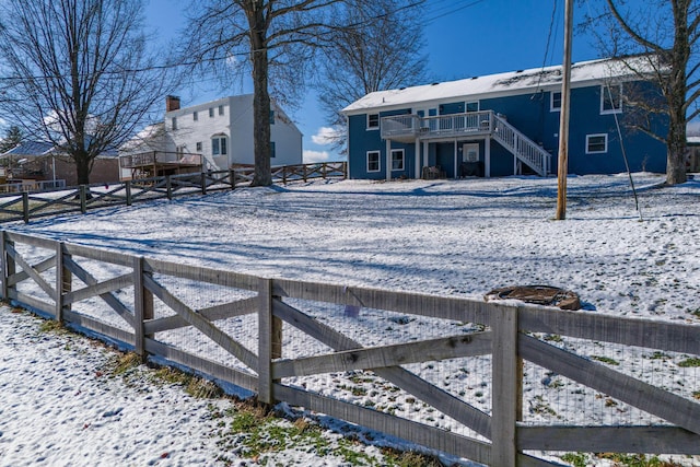 snowy yard with a wooden deck, stairs, and fence