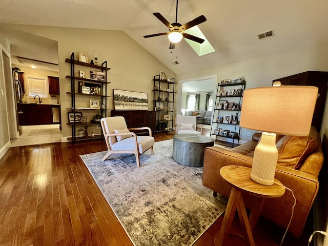 living area featuring wood-type flooring, lofted ceiling with skylight, sink, and ceiling fan