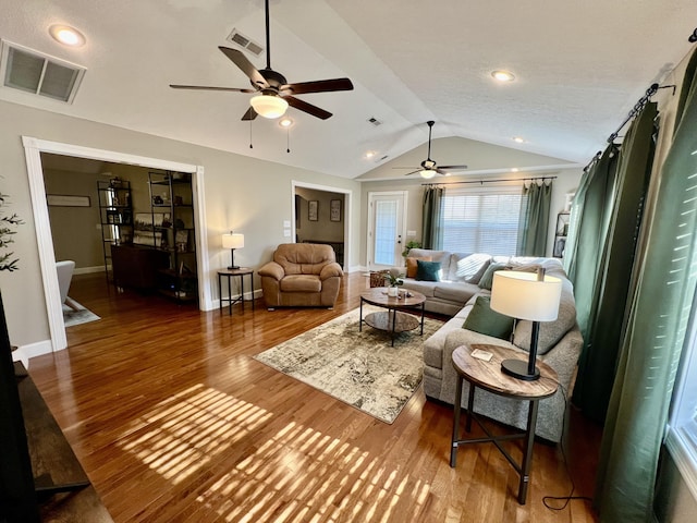 living room featuring wood-type flooring, lofted ceiling, and ceiling fan