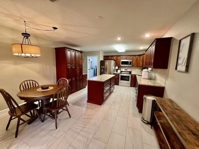 kitchen with decorative light fixtures, light stone countertops, a center island, and appliances with stainless steel finishes