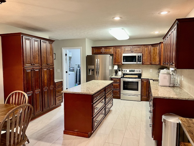 kitchen featuring a kitchen island, appliances with stainless steel finishes, light stone counters, and decorative backsplash