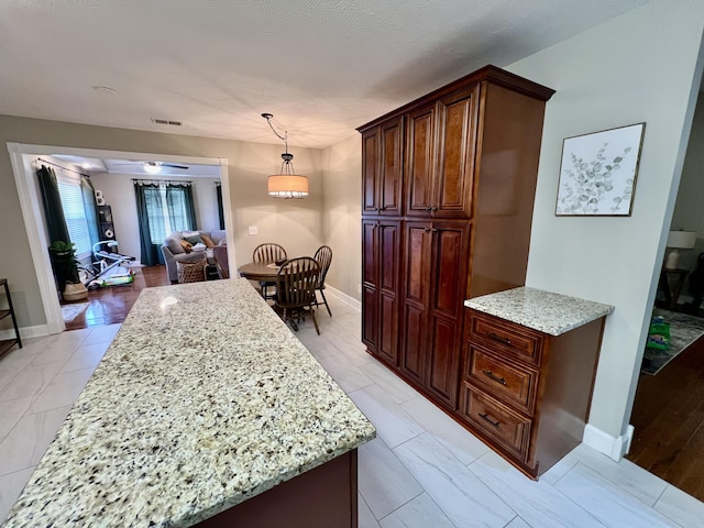 kitchen with light stone counters and hanging light fixtures