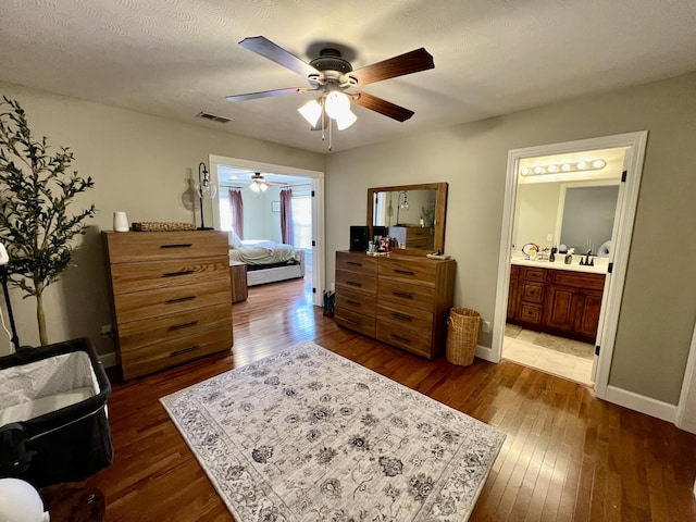 bedroom featuring ceiling fan, dark wood-type flooring, and ensuite bath