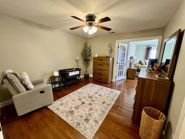 living area featuring dark wood-type flooring, ceiling fan, and french doors