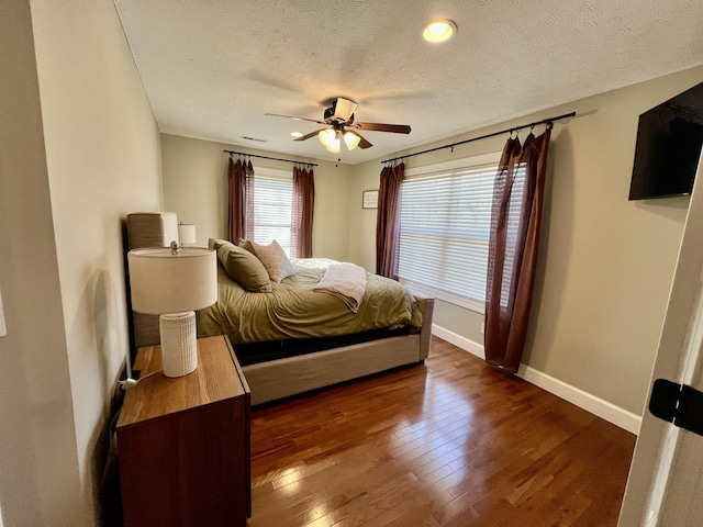 bedroom featuring ceiling fan, dark wood-type flooring, and a textured ceiling