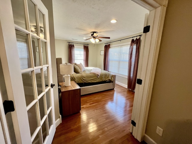 bedroom with hardwood / wood-style floors, a textured ceiling, and ceiling fan