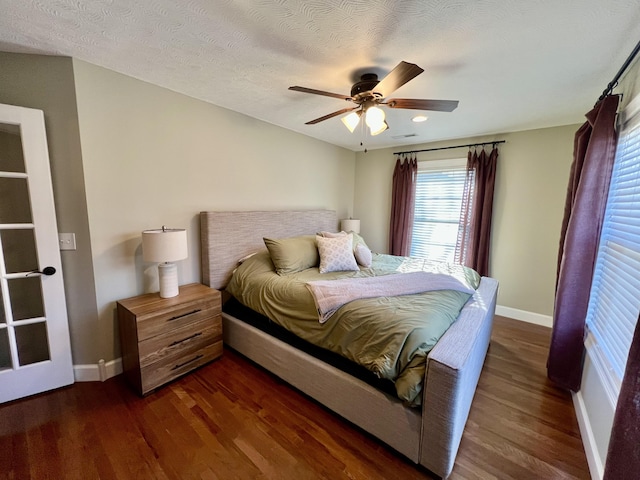 bedroom featuring ceiling fan, dark wood-type flooring, and a textured ceiling