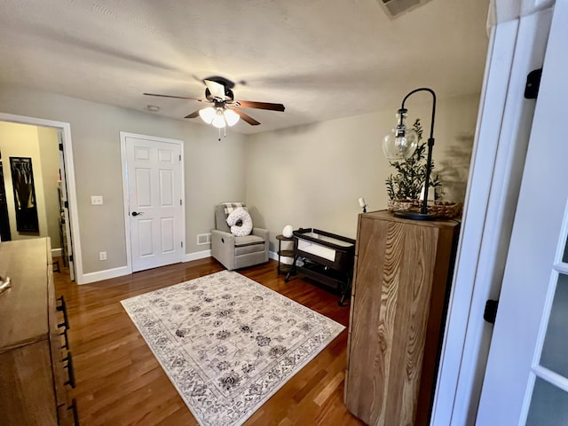 living area featuring dark wood-type flooring and ceiling fan