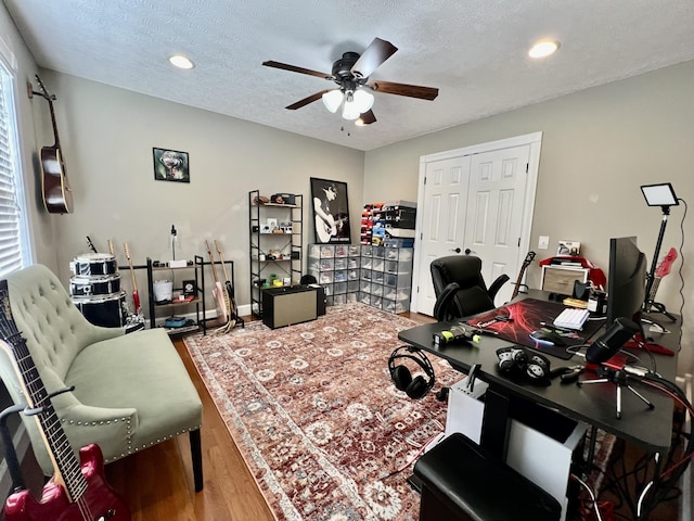 home office featuring ceiling fan, hardwood / wood-style flooring, and a textured ceiling