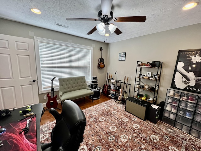 home office with ceiling fan, hardwood / wood-style floors, and a textured ceiling