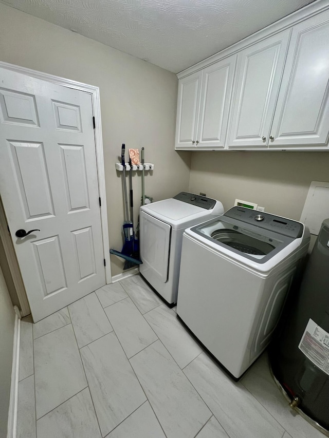 clothes washing area featuring cabinets, washing machine and dryer, and a textured ceiling