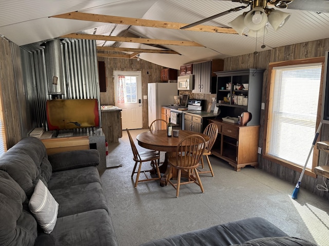 dining space with vaulted ceiling with beams, ceiling fan, and wood walls