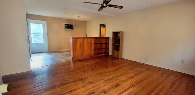 unfurnished room featuring ceiling fan, a wall mounted AC, and hardwood / wood-style floors