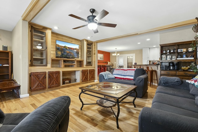 living room with ceiling fan with notable chandelier and light hardwood / wood-style flooring