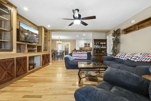 living room with ceiling fan with notable chandelier and light wood-type flooring