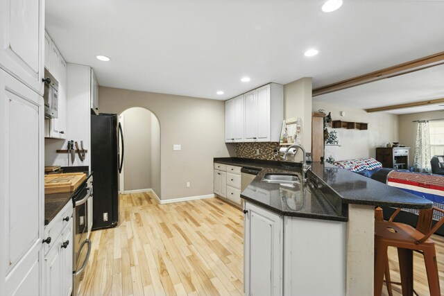 kitchen featuring black refrigerator, kitchen peninsula, sink, and white cabinets