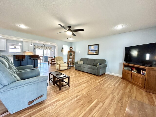 living room featuring a textured ceiling, light hardwood / wood-style floors, and ceiling fan