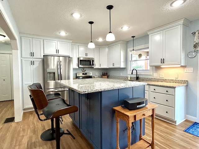 kitchen featuring stainless steel appliances, hanging light fixtures, and white cabinets