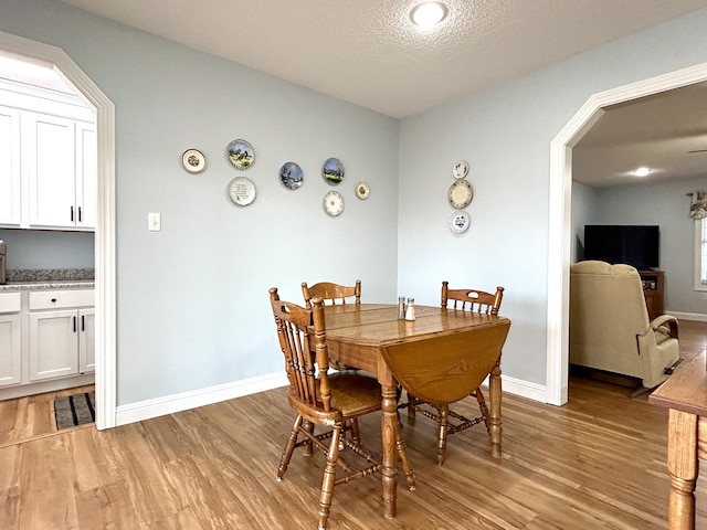 dining room with light hardwood / wood-style floors and a textured ceiling