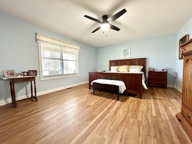 bedroom featuring ceiling fan, light hardwood / wood-style flooring, and a textured ceiling