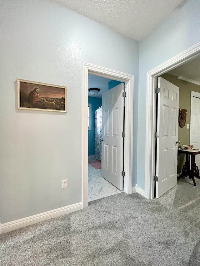 corridor featuring light carpet and a textured ceiling