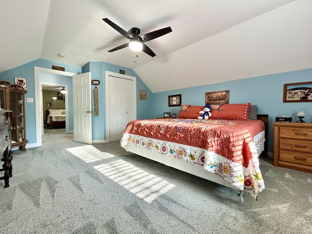 carpeted bedroom with lofted ceiling, ceiling fan, a closet, and a textured ceiling