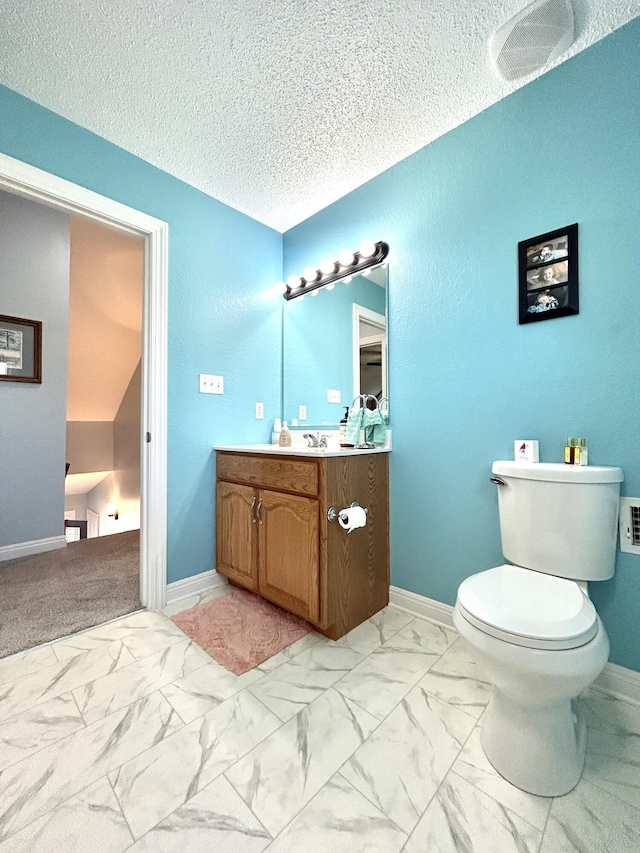 bathroom featuring vanity, toilet, and a textured ceiling