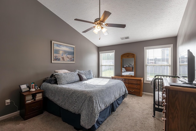 bedroom with light carpet, ceiling fan, vaulted ceiling, and a textured ceiling