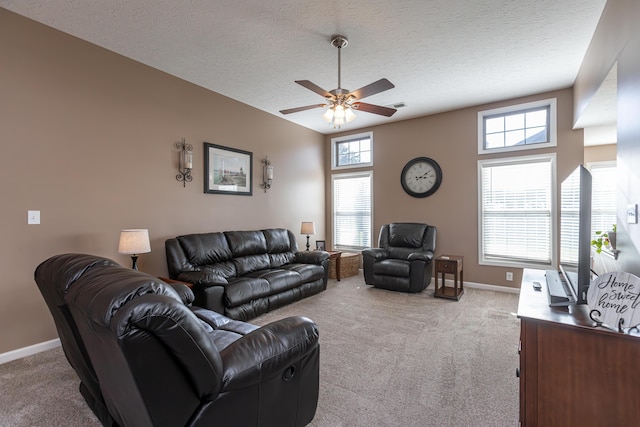 living room featuring ceiling fan, a textured ceiling, light carpet, and a wealth of natural light