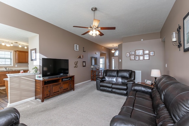 carpeted living room with sink, a textured ceiling, and ceiling fan