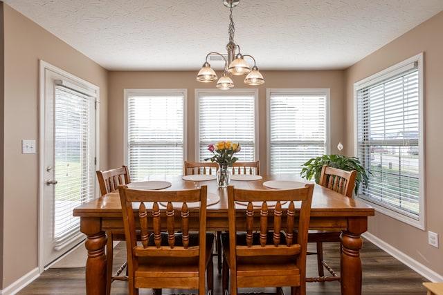 dining area featuring dark hardwood / wood-style flooring, a textured ceiling, a healthy amount of sunlight, and an inviting chandelier