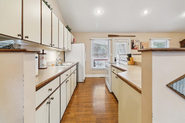 kitchen featuring white cabinetry, sink, white appliances, and light hardwood / wood-style flooring