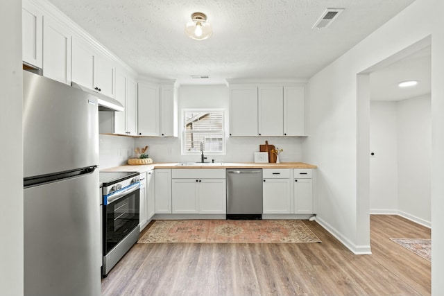 kitchen featuring sink, light hardwood / wood-style floors, white cabinets, and appliances with stainless steel finishes