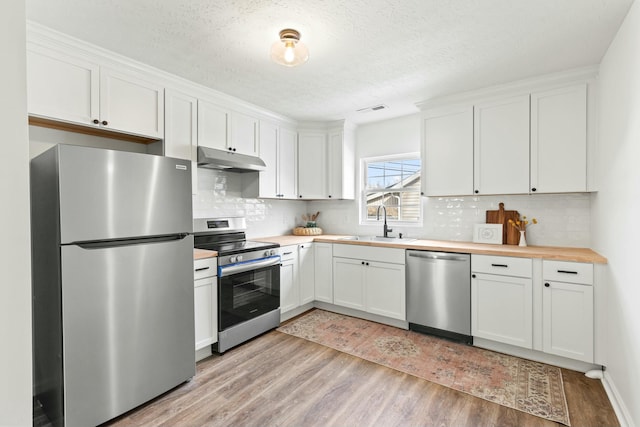 kitchen featuring butcher block counters, sink, white cabinets, stainless steel appliances, and light hardwood / wood-style flooring