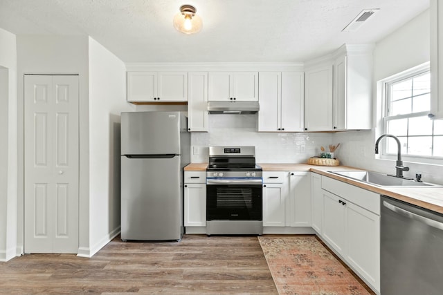 kitchen featuring white cabinetry, sink, decorative backsplash, stainless steel appliances, and light hardwood / wood-style flooring