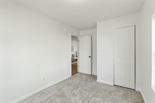 unfurnished bedroom featuring light colored carpet and a closet