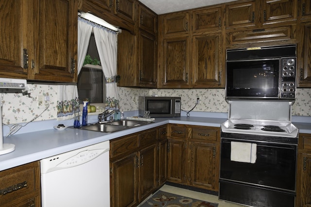 kitchen with dark brown cabinetry, dishwasher, sink, and electric range