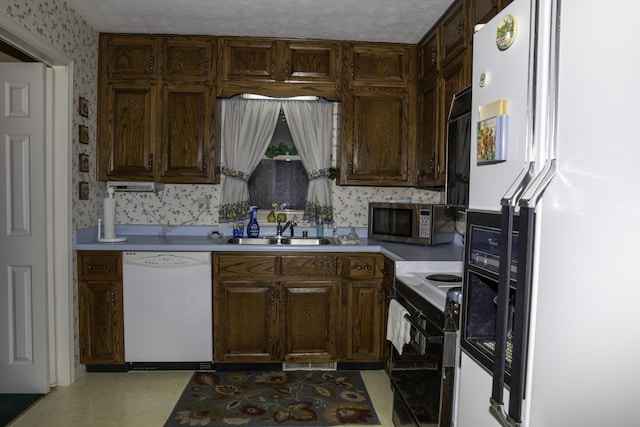 kitchen featuring sink, white appliances, and dark brown cabinets