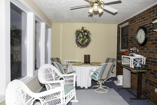 interior space with ceiling fan, brick wall, and a textured ceiling