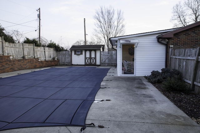 view of swimming pool with a patio and a storage unit